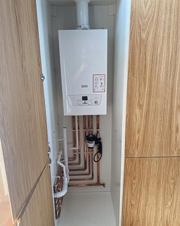 Wall-hung boiler neatly installed in a cupboard with tidy copper pipework