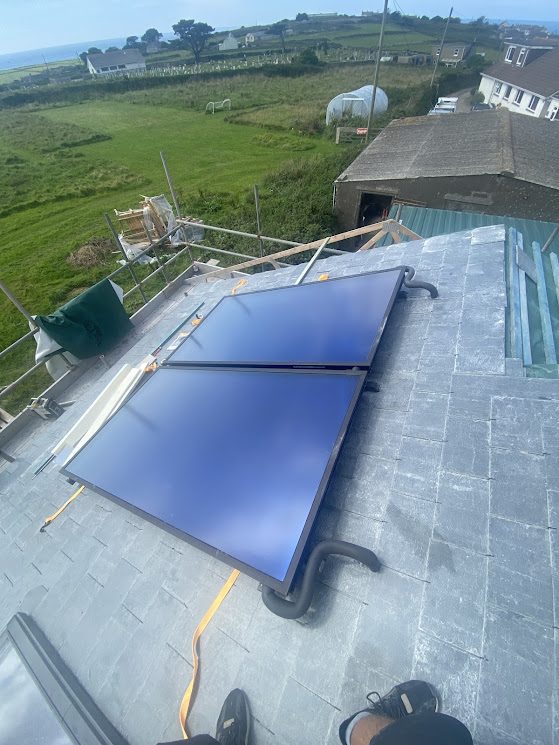 Solar thermal panels installed on a slate roof overlooking the Cornish coast
